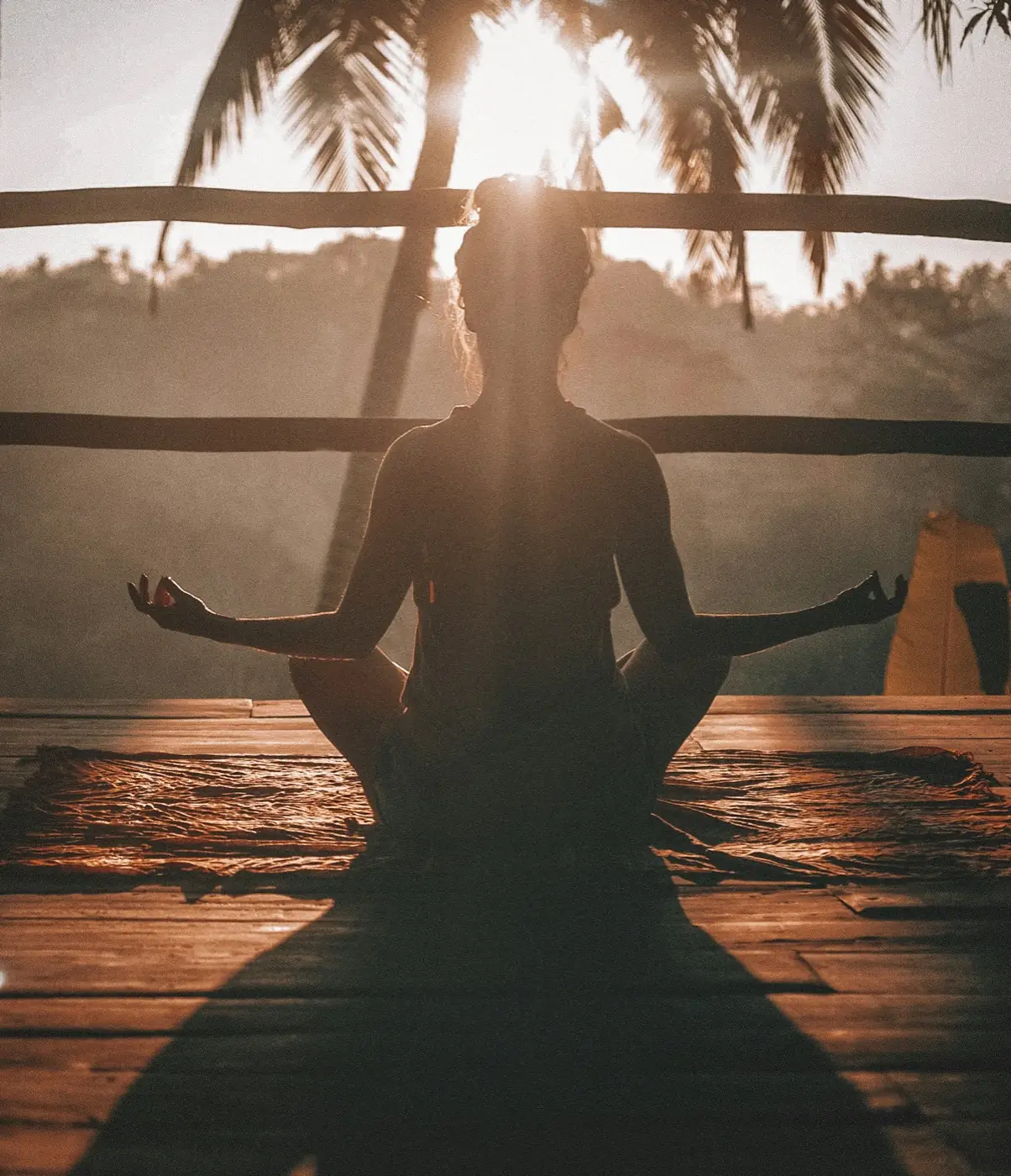 A person seated in meditation at sunrise